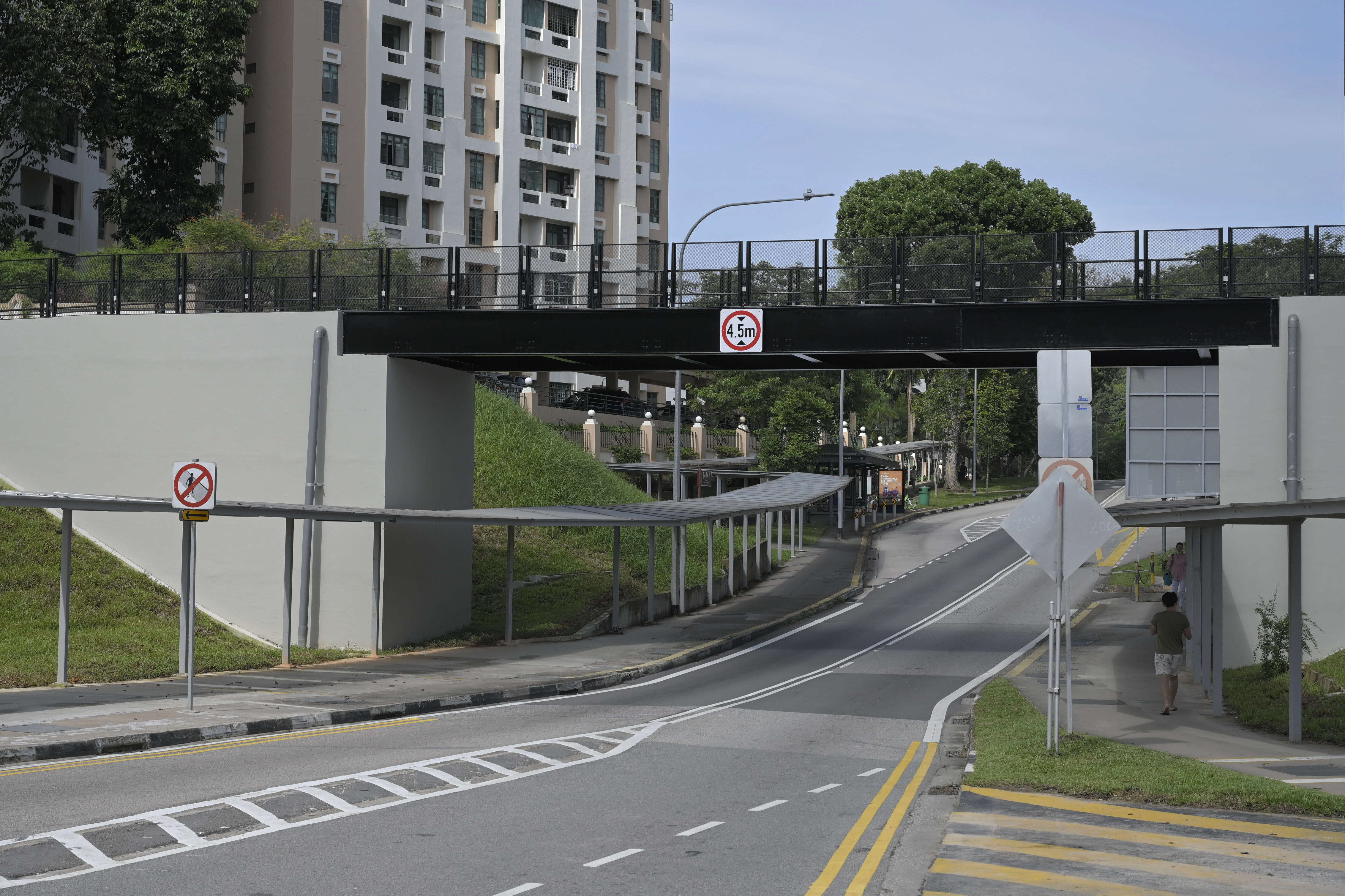 An overpass with a 4.5m height limit sign spans a road near a residential building and covered walkway.